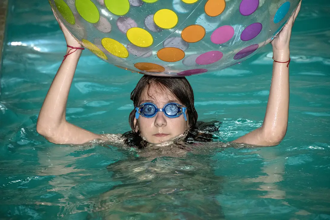 Copil cu minge de plajă în piscină